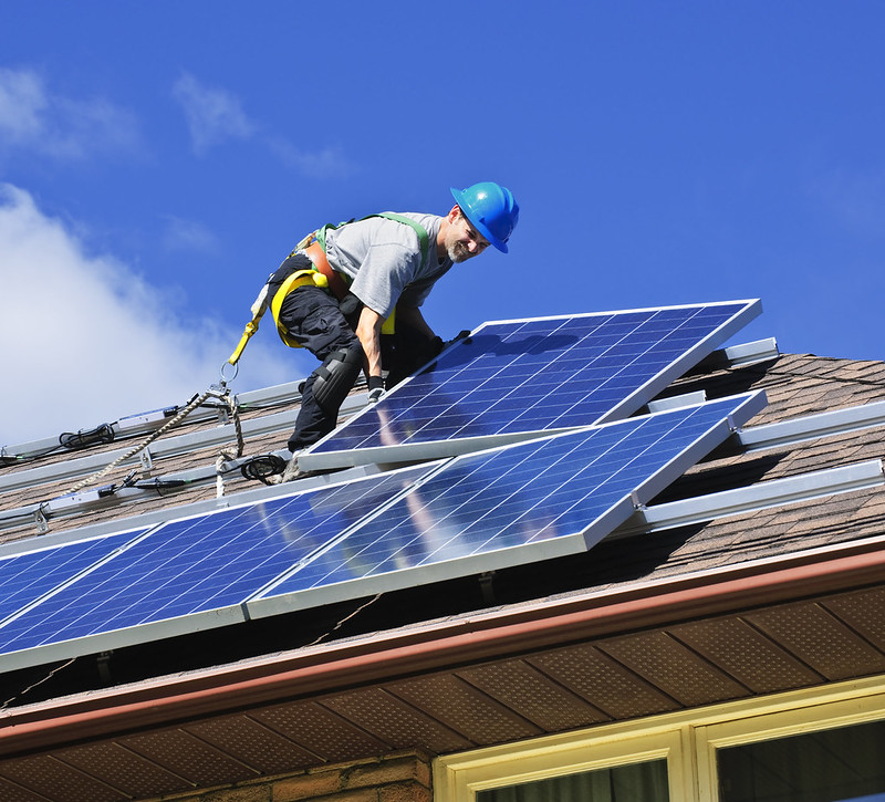 Foto: Instalare panouri solare. Bărbat care instalează panouri solare fotovoltaice cu energie alternativă pe acoperiș Sursa: Arhiva de imagini EE | Flickr