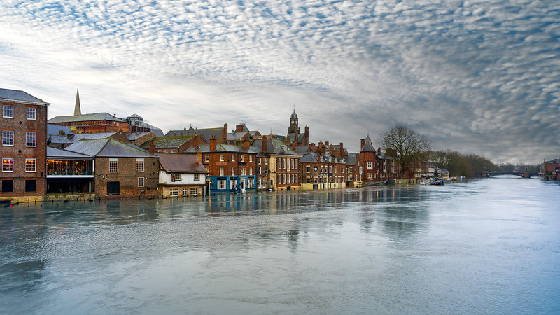 Foto: Inundatiile din York, UK, 10 decembrie 2023. Sursa@ Dale Cruse | Flickr În decembrie 2023, Yorkshire, Anglia, s-a confruntat cu inundații fără precedent, lăsând rezidenții și autoritățile confruntându-se cu consecințele. Potrivit rapoartelor meteo, ploile necontenite, cuplate cu terenuri saturate, au dus la creșterea nivelului apei în râuri și pâraie, inundand afacerile și drumurile din regiune. Inundațiile, descrise drept „neobișnuite” de meteorologi, au subliniat impactul tot mai mare al fenomenelor meteorologice extreme alimentate de schimbările climatice. Comunitățile s-au adunat împreună pentru a sprijini familiile afectate, evidențiind rezistența și solidaritatea locuitorilor din Yorkshire în fața adversității.