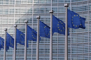 Steagurile Uniunii Europene fluturând în fața clădirii Berlaymont, sediul Comisiei Europene din Bruxelles — centrul deciziilor care modelează politicile europene de mediu și climă. Sursa foto:Guillaume Périgois/Unsplash